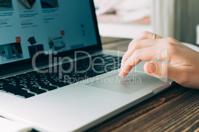 Woman working with laptop placed on wooden desk