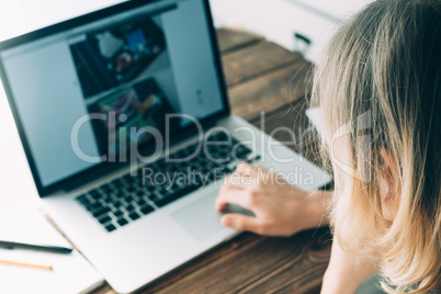 Woman working with laptop placed on wooden desk