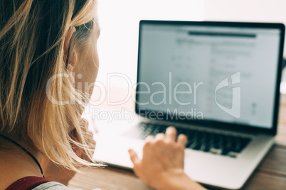 Woman working with laptop placed on wooden desk