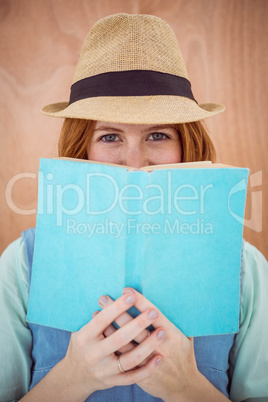 blue eyed hipster woman looking over the top of a book