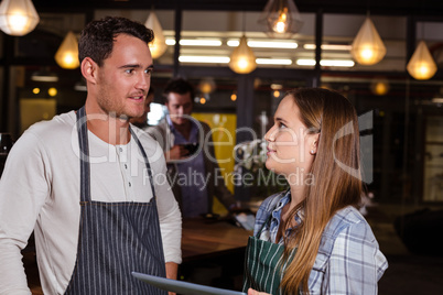 Smiling baristas talking while holding tablet