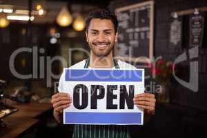 Smiling barista holding open sign