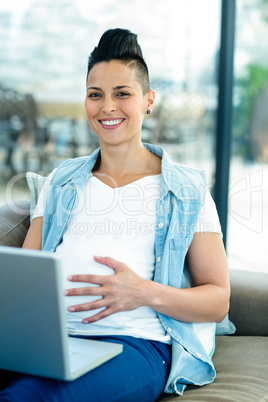 Portrait of pregnant woman relaxing on sofa with her laptop Portrait of pregnant woman relaxing on sofa with her laptop