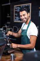 Smiling waiter making cup of coffee