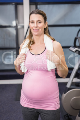 Smiling pregnant woman standing with towel around neck