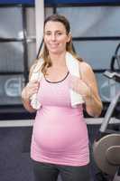 Smiling pregnant woman standing with towel around neck