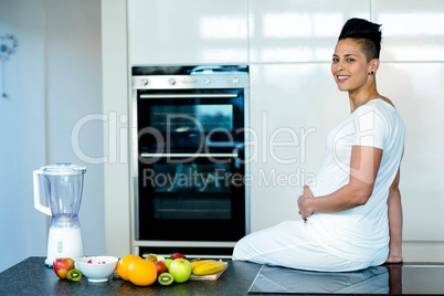 Pregnant woman sitting on kitchen worktop