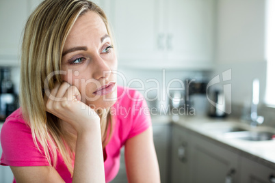 Thoughtful blonde woman leaning on her counter