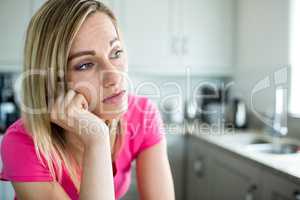 Thoughtful blonde woman leaning on her counter