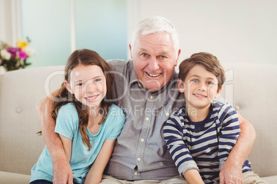 Grandfather and grandchildren sitting together on sofa