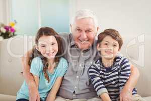 Grandfather and grandchildren sitting together on sofa