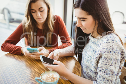 Friends using smartphone and having coffee