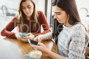 Friends using smartphone and having coffee