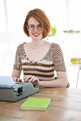smiling hipster woman typing on her typewriter