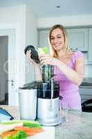 Blonde woman preparing a smoothie in the kitchen