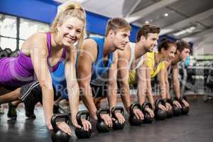 Fitness class in plank position with dumbbells