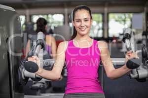 Fit woman using weight machine