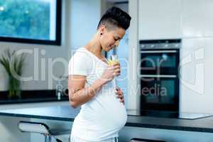 Pregnant woman drinking juice in kitchen