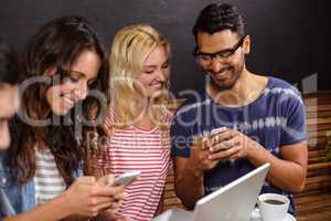 Smiling friends watching a smartphone together