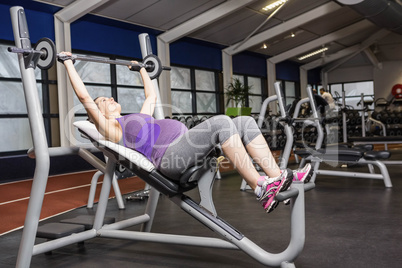 Smiling pregnant woman lifting barbell