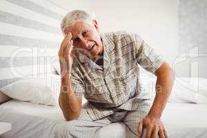 Frustrated senior man sitting on bed