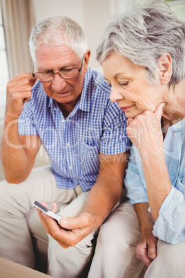 Sad senior couple looking at mobile phone