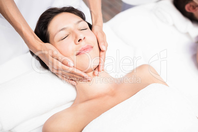 Woman receiving a face massage from masseur