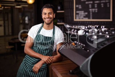 Smiling barista leaning against counter