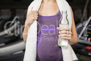 Mid section of pregnant woman holding bottle of water