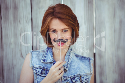 beautiful hipster woman holding a fake mustache
