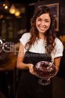 Pretty waitress presenting a chocolate cake