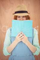 smiling hipster woman looking out over a book