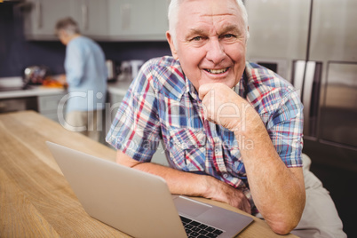 Portrait of happy senior man using laptop and woman working in k