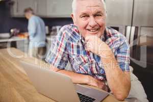 Portrait of happy senior man using laptop and woman working in k