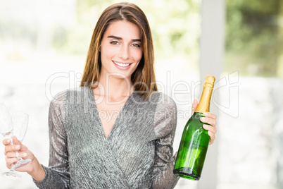 Portrait of beautiful woman holding champagne bottle and glass