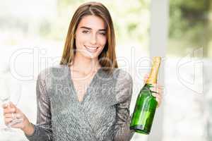 Portrait of beautiful woman holding champagne bottle and glass