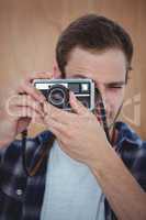 Handsome hipster taking picture with retro camera