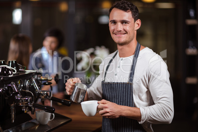 Smiling barista preparing cappuccino