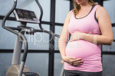 Mid section of pregnant woman touching her belly