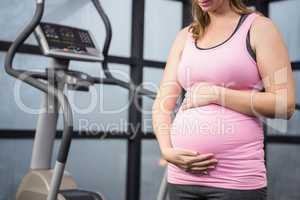 Mid section of pregnant woman touching her belly