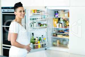 Portrait of pregnant woman looking for food in fridge