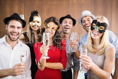 Friends holding champagne glasses laughing at camera