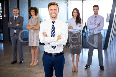 Businessman smiling at camera while his colleagues standing in b