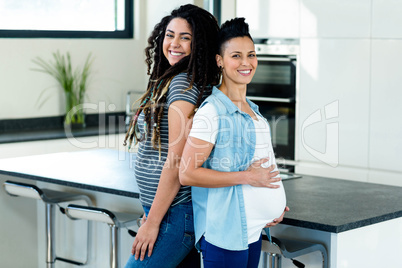 Pregnant lesbian couple standing back to back