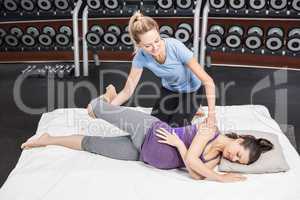 Pregnant woman stretching with her trainer