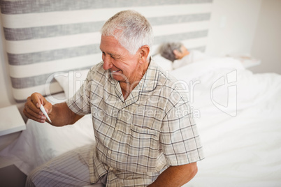 Happy senior man holding a thermometer