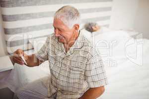 Happy senior man holding a thermometer