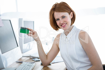 smiling hipster business woman holding up a credit card
