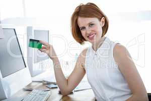 smiling hipster business woman holding up a credit card