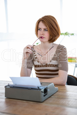 thoughtful  hipster sitting in front of a typewriter